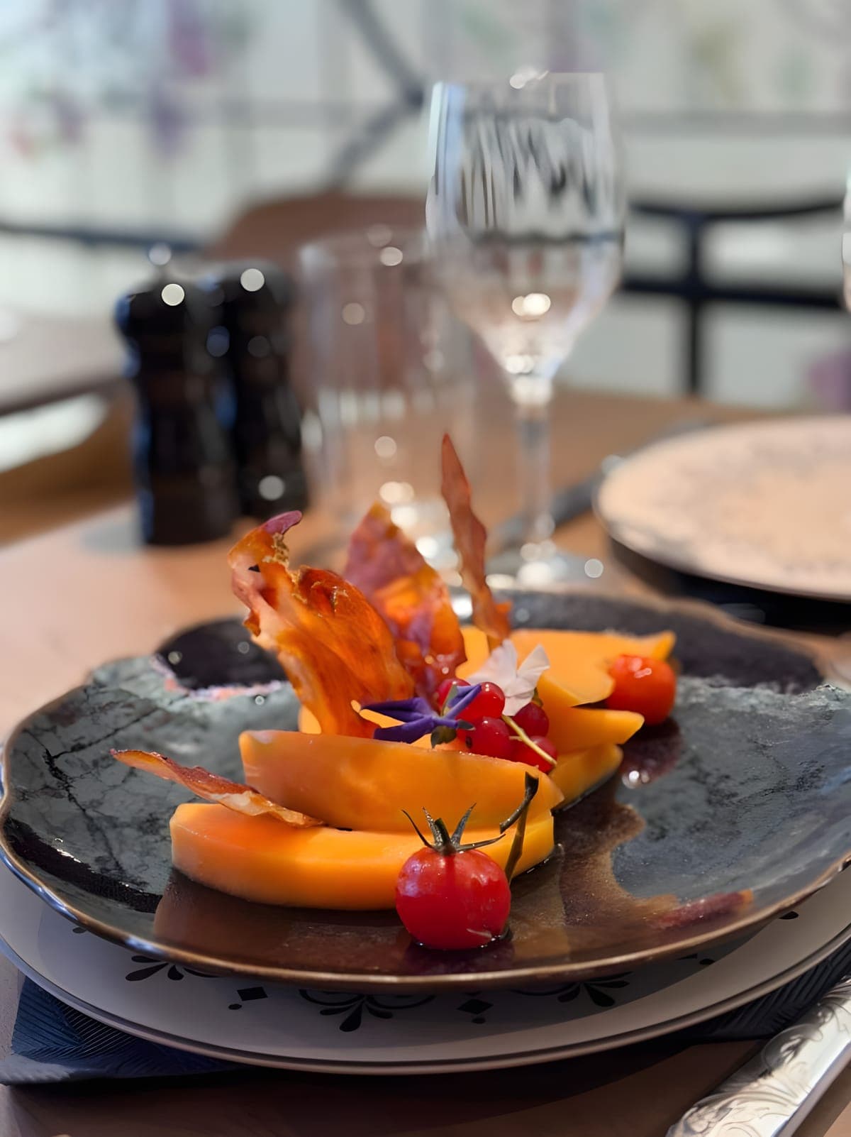 Melon, chips de jambon de pays et fleurs comestibles, à table